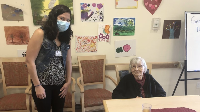 An elderly lady sitting with a young lady in activity room